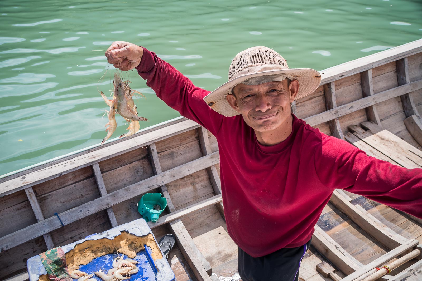 Een Thaise visser in een long tail boot verkoopt garnalen